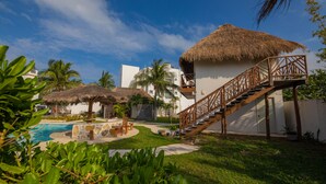 A resort with a swimming pool, thatched-roof structures, and a staircase leading to a balcony. - Hotel & Beach Club Ojo de Agua (Puerto Morelos)