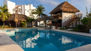 A swimming pool with a thatched-roof structure, a staircase, and a palm tree. - Hotel & Beach Club Ojo de Agua (Puerto Morelos)