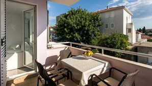 A balcony with a table, chairs, and a bowl of fruit. - Apartment Dupčić - Two Bedroom Apartment with Balcony (Dubrovnik)