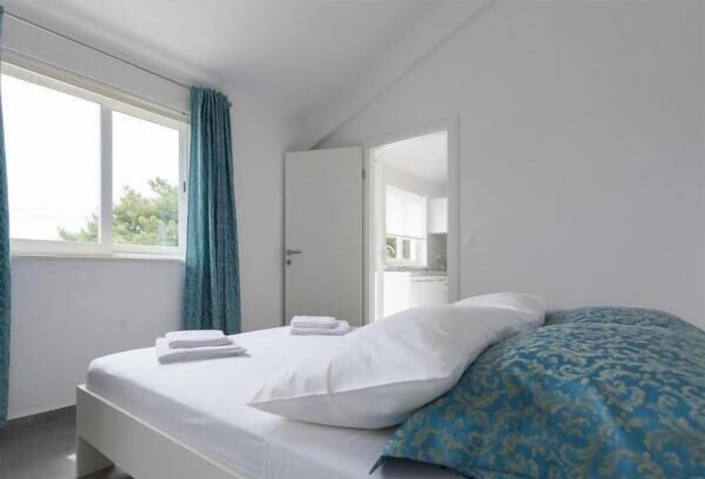 Une chambre d’hôtel avec un lit, une fenêtre avec des rideaux et une porte.