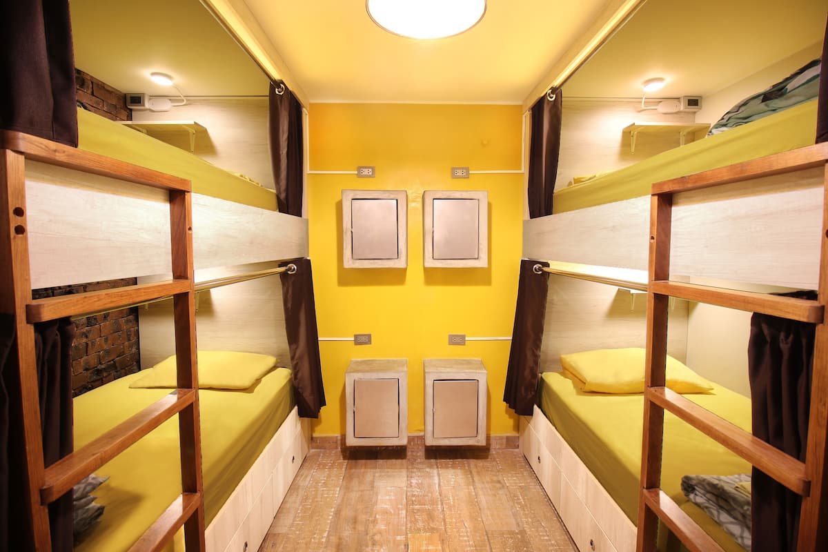 Una habitación pequeña con literas, una pared de ladrillo y una pared amarilla.
