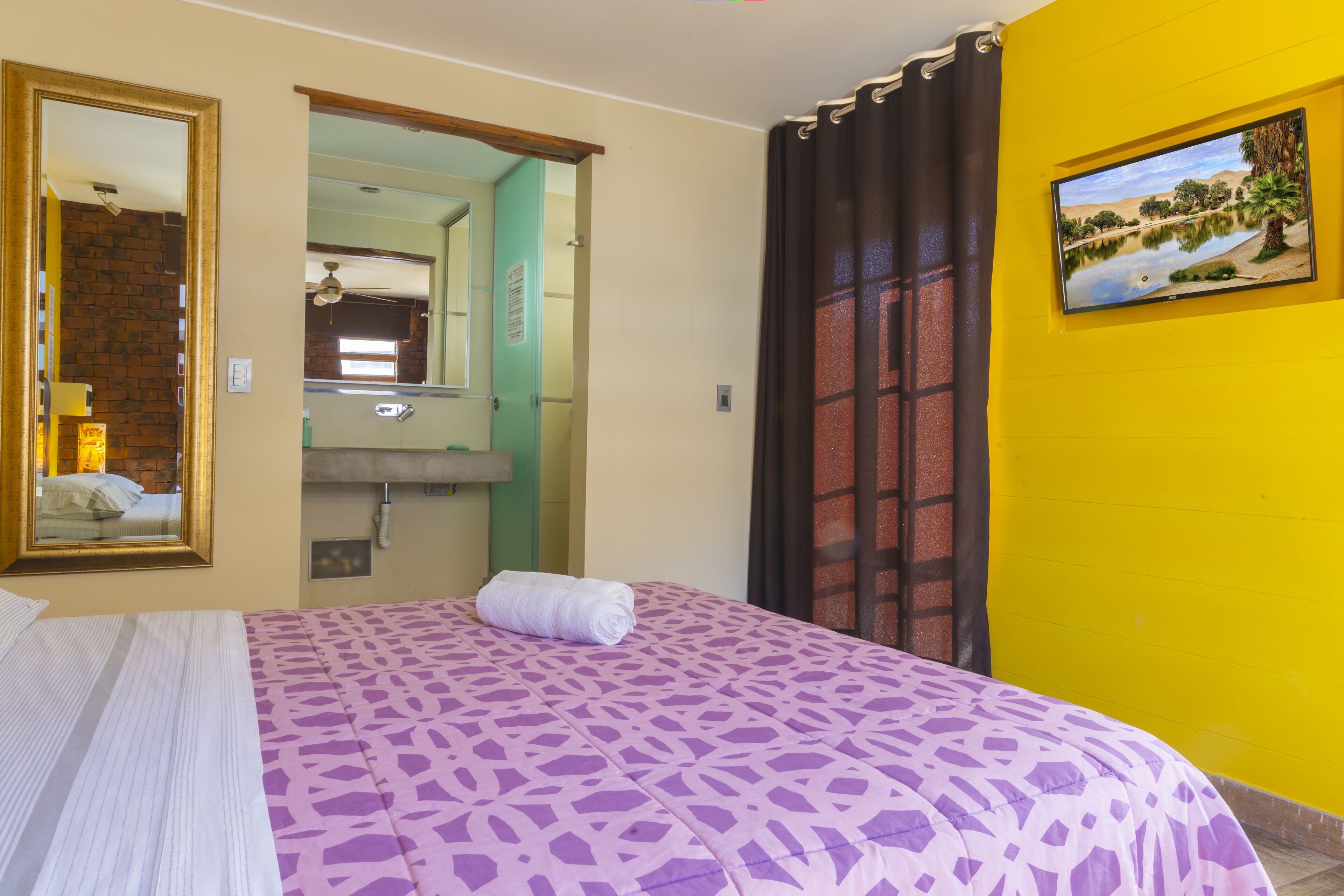 Un dormitorio con cama, espejo, lavamanos y un cuadro en la pared.