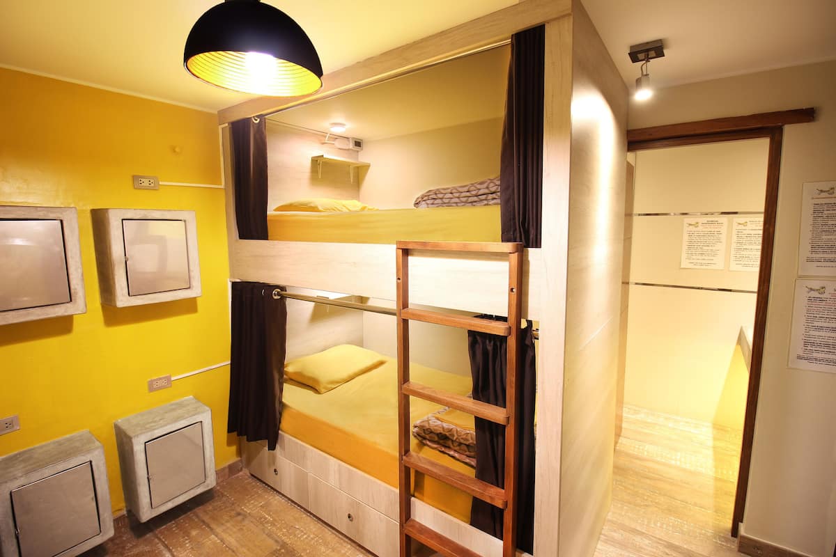 Habitación con literas, un escritorio pequeño y un espejo.