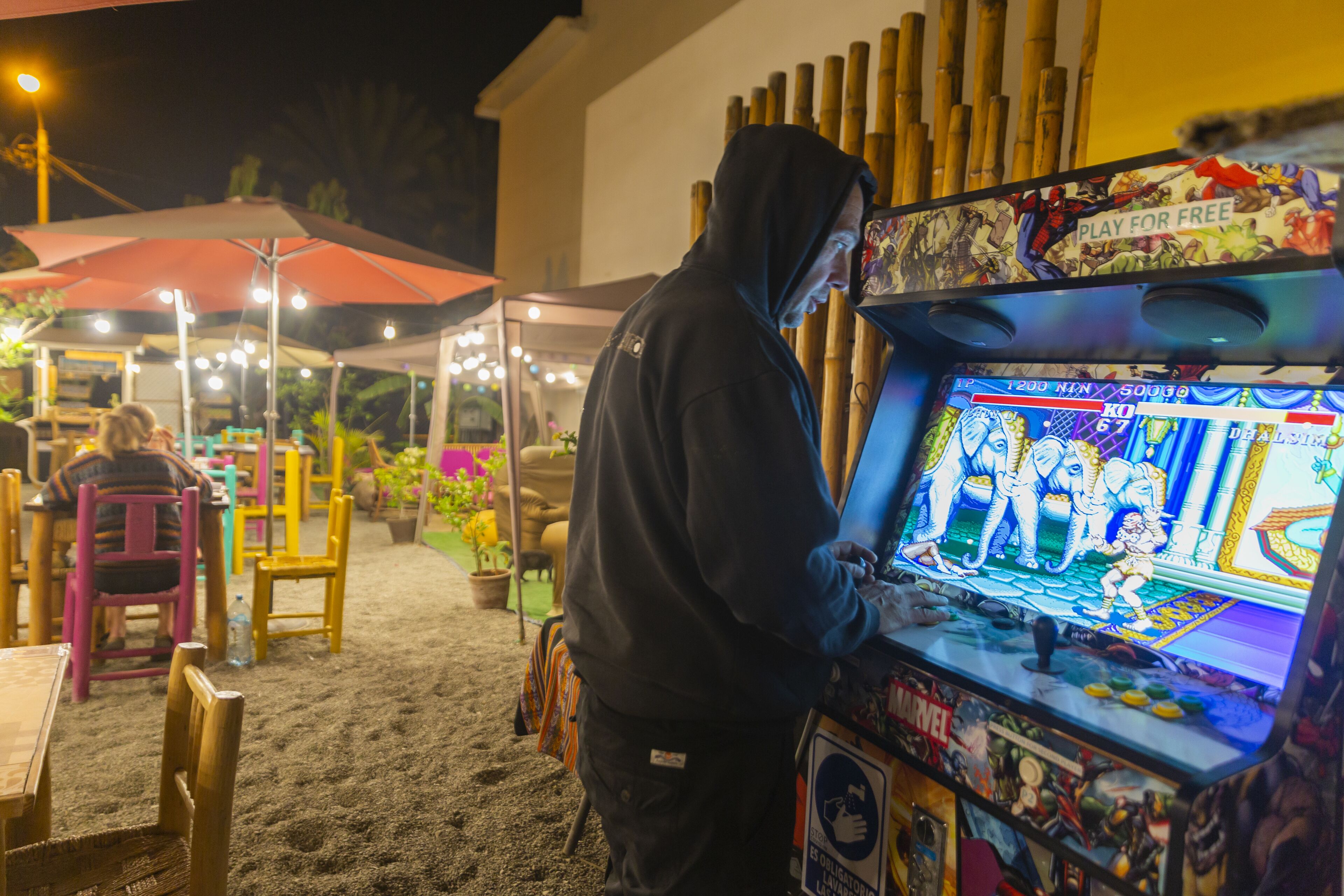 A person playing a video game at an outdoor arcade.