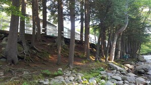 A forested area with a wooden deck overlooking a rocky stream. - Franconia Notch Motel (Lincoln)