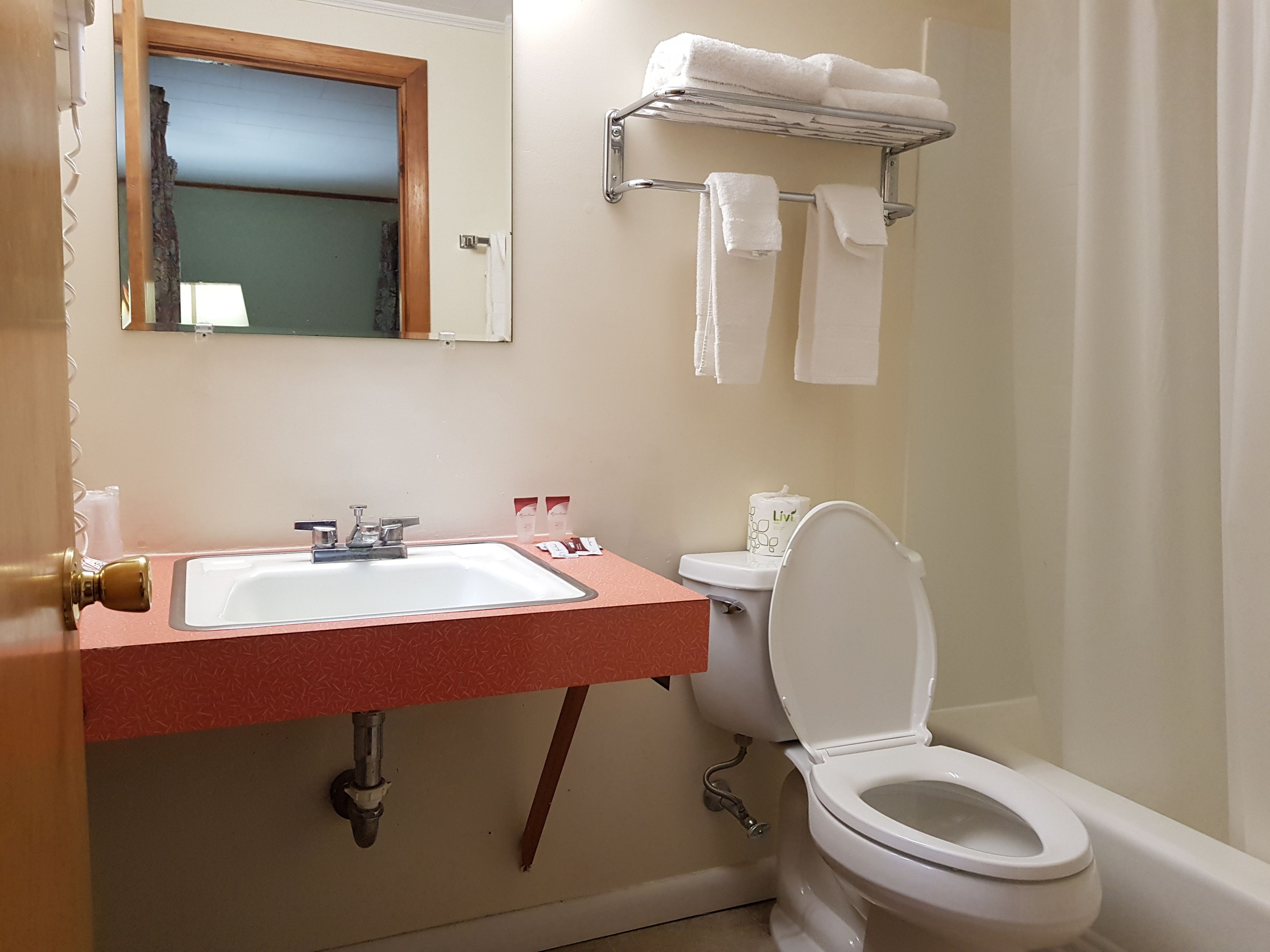 Un baño con lavamanos, inodoro y toallero.