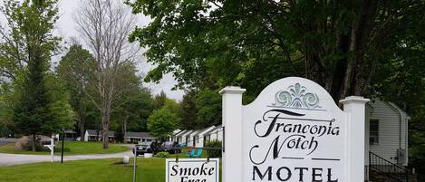 A motel sign with "Francoia Notch" and "Smoke Free" labels, surrounded by greenery and a row of cabins.