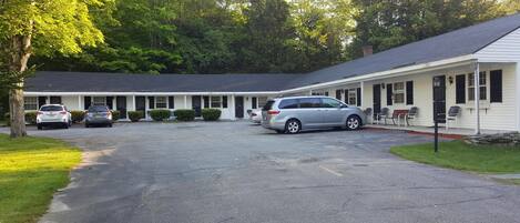 A motel with a central parking area, a covered walkway, and a row of rooms with a single-story structure.