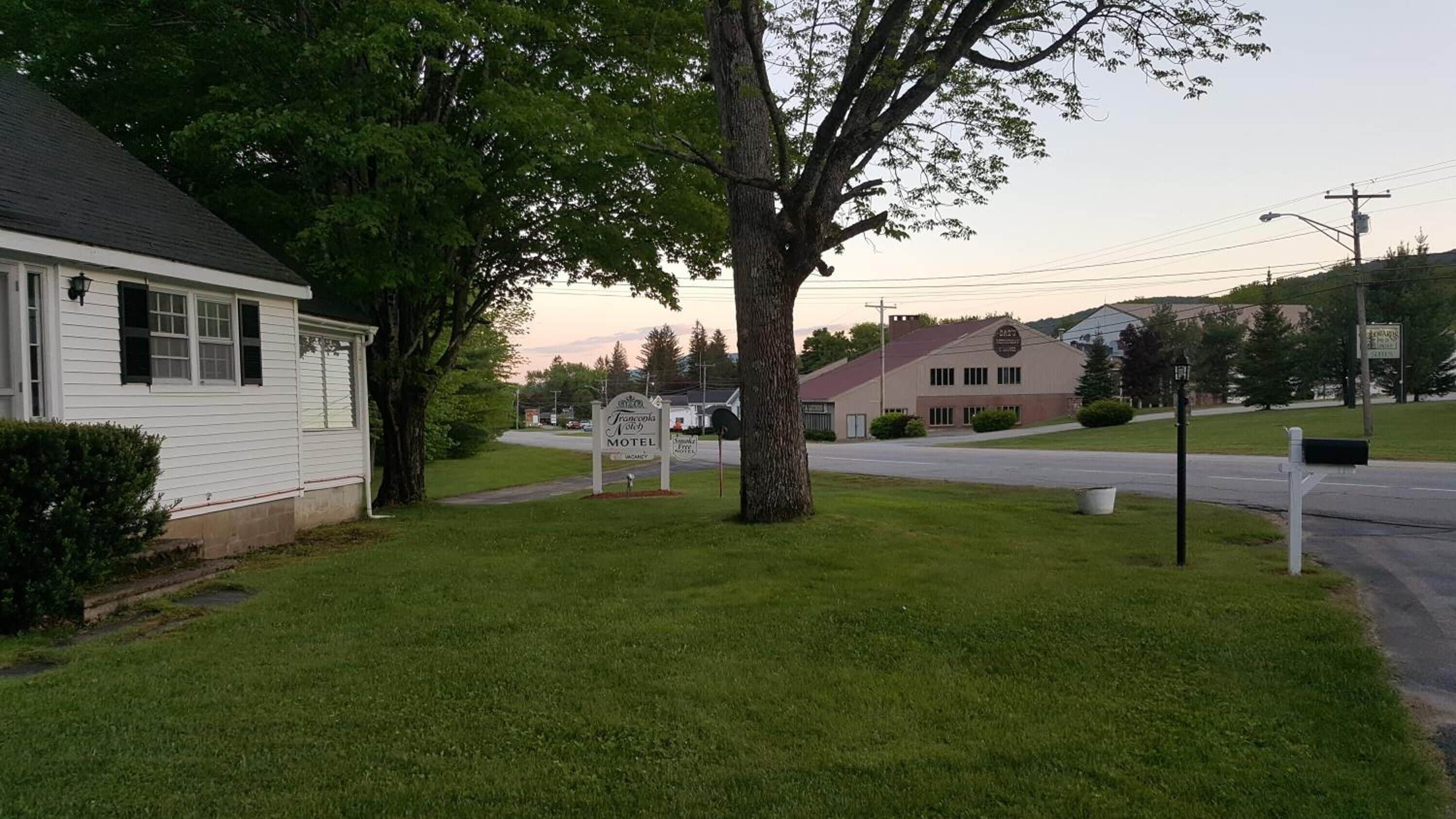 A motel with a signboard, a grassy lawn, and a building in the background.