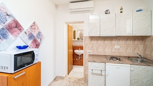 Cozinha compacta com micro-ondas, pia e armários.