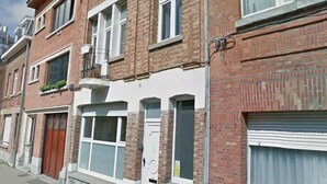 Une rangée de maisons de ville aux façades en briques, aux fenêtres à cadre blanc et dont la porte d’entrée est bien visible.