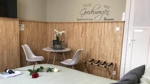 Une pièce comprenant un lit, une petite table avec des chaises, un porte-manteau fixé au mur et un panneau décoratif.