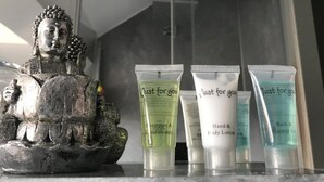 Une statue de Bouddha et trois tubes de produits de soins pour la peau sont posés sur un comptoir en marbre.