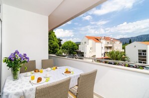 Een balkon met een ontbijtje erop, met uitzicht op een woonwijk met huizen en bergen.