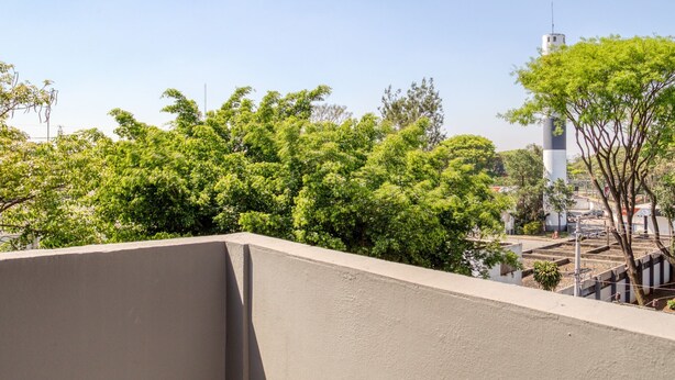 A concrete structure with a clear view of a white tower with a black top, surrounded by lush green trees. - HOTEL PAULISTANO Center Norte (São Paulo)