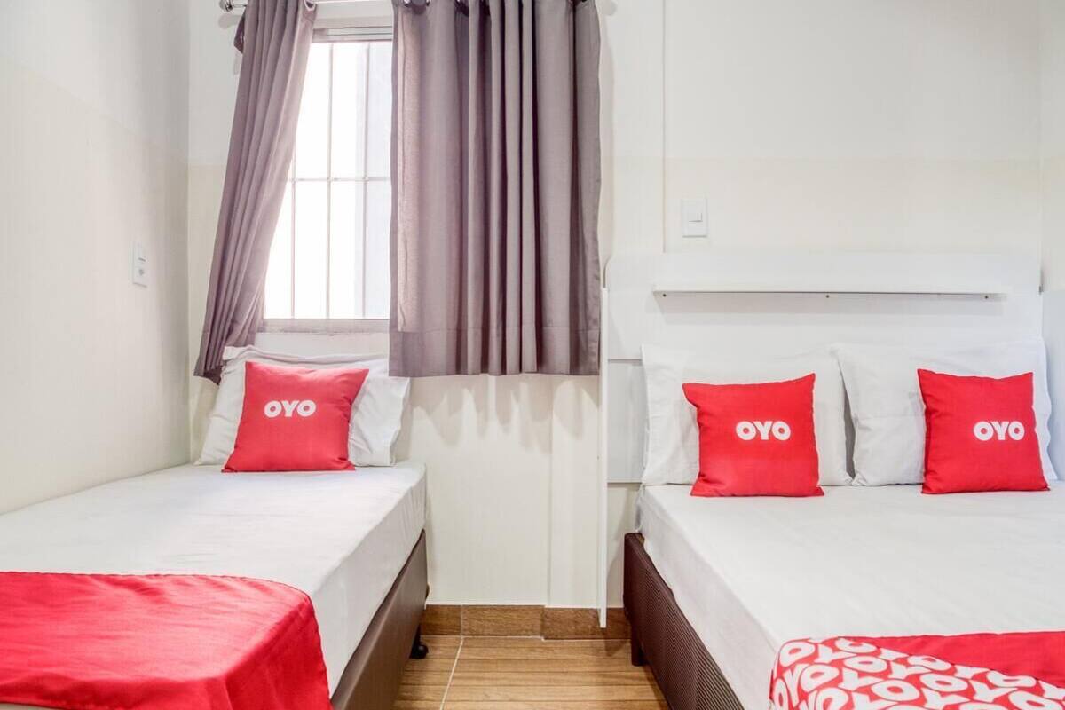 Una habitación de hotel con dos camas individuales, cada una con una almohada roja de la marca OYO.