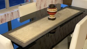 Un coin repas avec une table à plateau en verre, des chaises blanches et un vase décoratif.