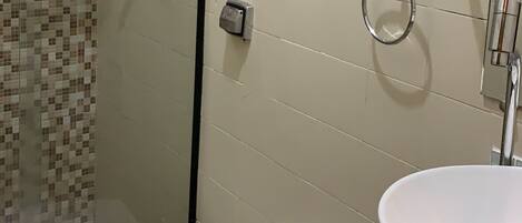 A bathroom with a toilet, sink, and hairdryer mounted on the wall.