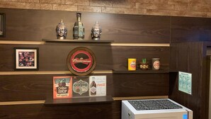 Une vitrine de café ornée d’enseignes Budweiser, Amstel et Stella Artois, ainsi que d’une enseigne Coca-Cola, avec en plus une affiche encadrée du café et un moulin à café.