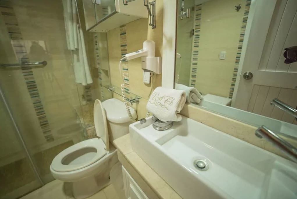 A bathroom with a toilet, sink, and mirror.