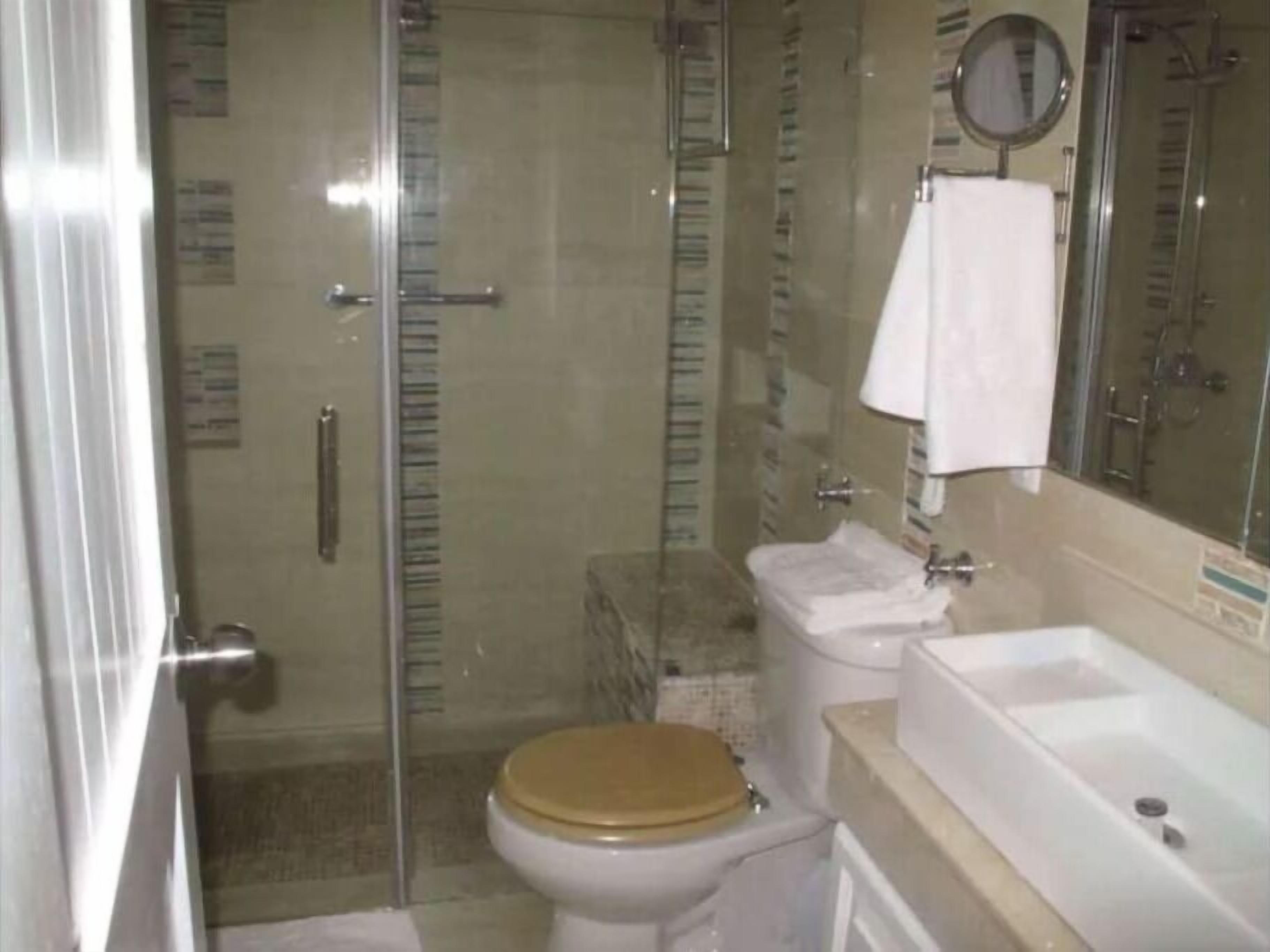 Un baño con inodoro, cabina de ducha, lavamanos y espejo.
