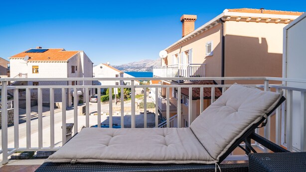 A balcony with a cushioned chair and a view of neighboring buildings and mountains. - Apartments Senjo - One Bedroom Apartment with Balcony and Sea View (4 adults) (Cavtat)