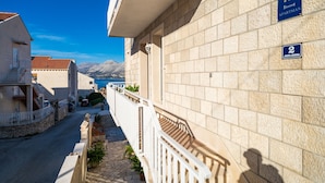 A building with a stone facade, a balcony with a white railing, and a sign indicating it is an apartment. - Apartments Senjo - One Bedroom Apartment with Balcony and Sea View (4 adults) (Cavtat)