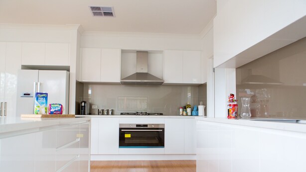 A modern kitchen with white cabinetry, a built-in oven, and a stainless steel range hood. - 5 Bedroom | 3 Bathroom Holiday Home near Glen Waverley with WIFI and NETFLIX (Forest Hill)