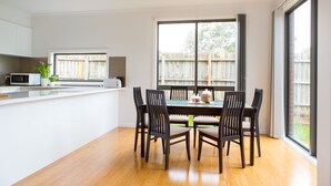 A modern kitchen with a dining area, large windows, and a view of a backyard. - 5 Bedroom | 3 Bathroom Holiday Home near Glen Waverley with WIFI and NETFLIX (Forest Hill)