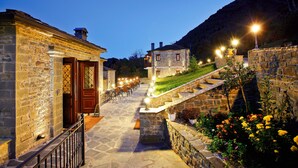 A stone building with a wooden door and a staircase leading to a higher level. - Hotel Athina (Zagori)