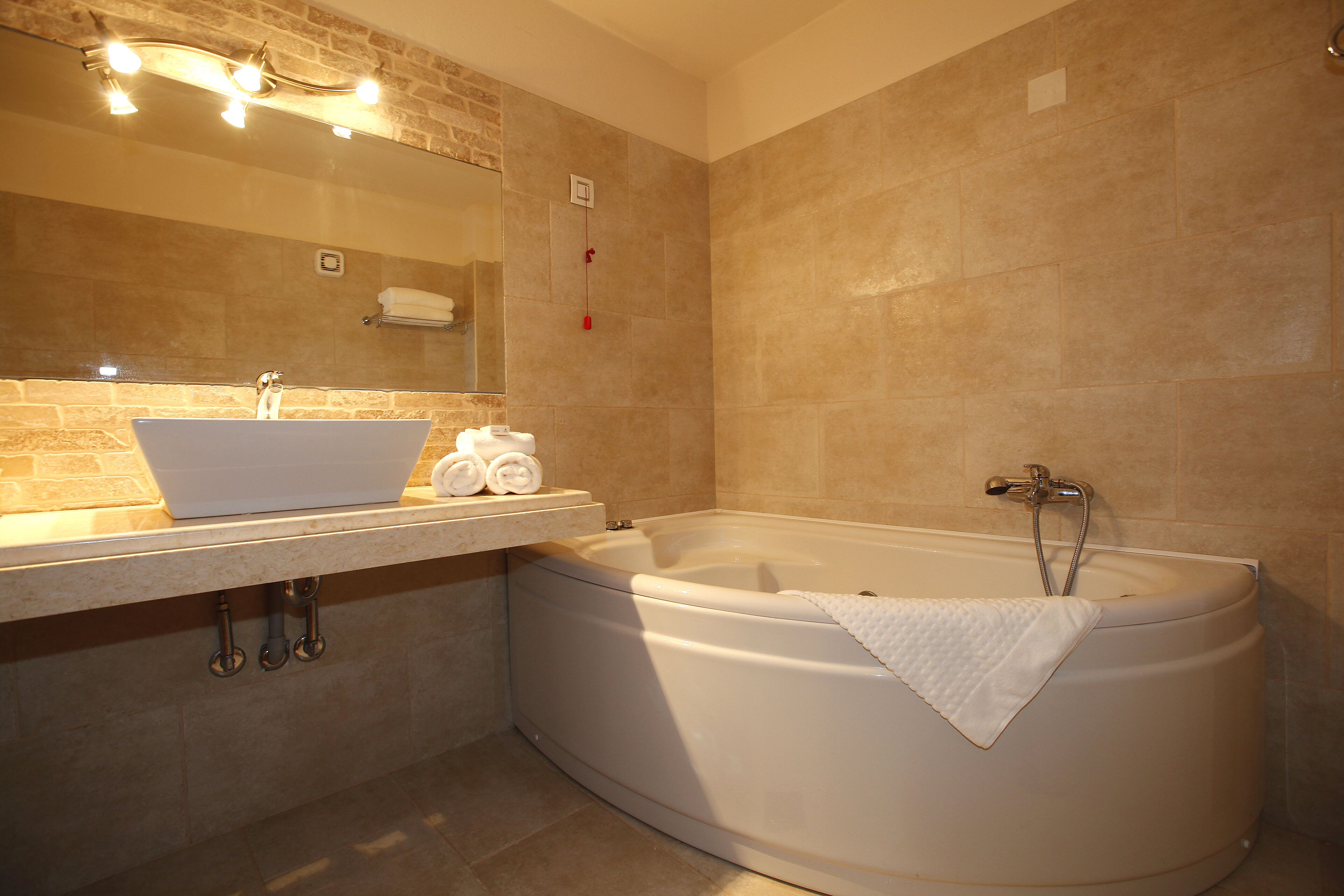 A bathroom with a sink, mirror, and bathtub.