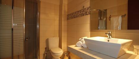 Un baño con cabina de ducha de vidrio, inodoro, lavabo con espejo y toallero.