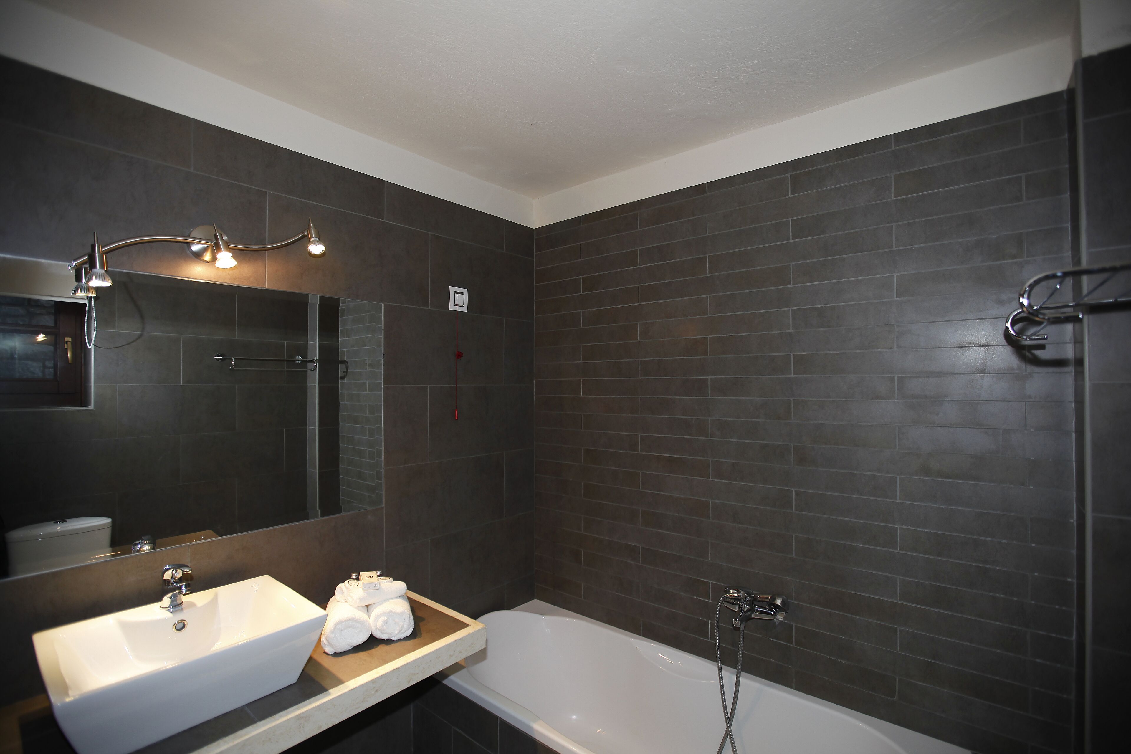 Une salle de bain moderne avec un lavabo blanc, un grand miroir et une baignoire.