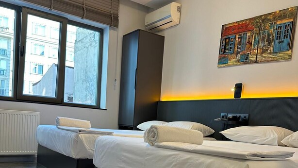 A modern hotel room with a large bed, a small desk, and a window with a city view. - Grand FM Hotel (Istanbul)