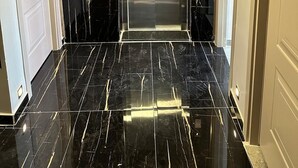 A modern elevator with a glass door, flanked by black marble walls and a polished floor. - Grand FM Hotel (Istanbul)