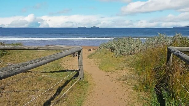 A dirt path leading to a beach with a wooden fence on one side. - Seaside Living, Steps to the Beach (LONG BEACH)