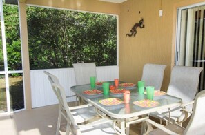 Enjoy meals al fresco in a patio area with a table for four, surrounded by comfortable seating and a decorative wall feature.