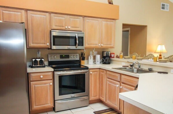 Enjoy cooking in this well-equipped kitchen with a refrigerator, microwave, oven, sink, and coffee maker.