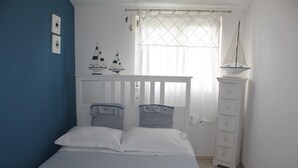 Un dormitorio con cama, cómoda y dos adornos de velero.