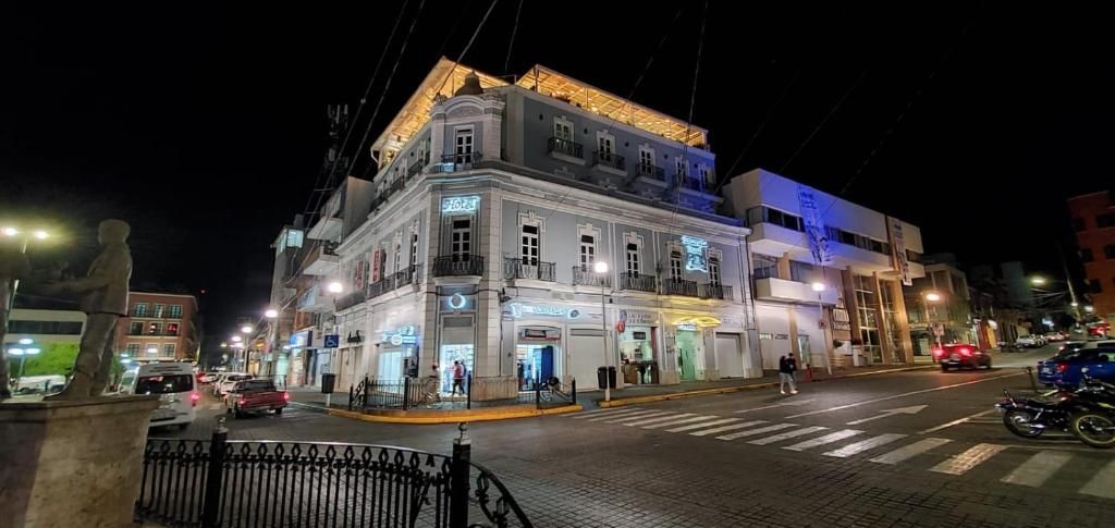 A multi-story building with illuminated signage, a street in front, and a pedestrian crossing.