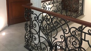 Une porte en bois, une colonne blanche et une rambarde en métal ornée de motifs complexes.