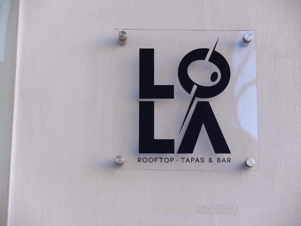 A sign with the text 'LOLA ROOFTOP TAPAS & BAR' mounted on a wall.