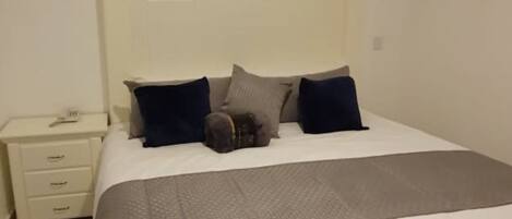A bedroom with a bed, a nightstand, and a dresser.