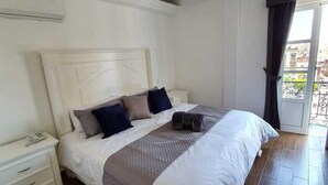 Une chambre à coucher avec un grand lit, une table de chevet et une fenêtre avec des rideaux.