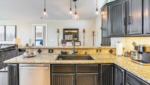 A kitchen with dark cabinets, a granite countertop, a sink, and a coffee maker. - Lakefront Retreat w/ Kayaks, Paddle Boards & Deck! (Nine Mile Falls)