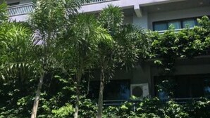 Um edifício com várias andares e varandas, rodeado por vegetação exuberante.