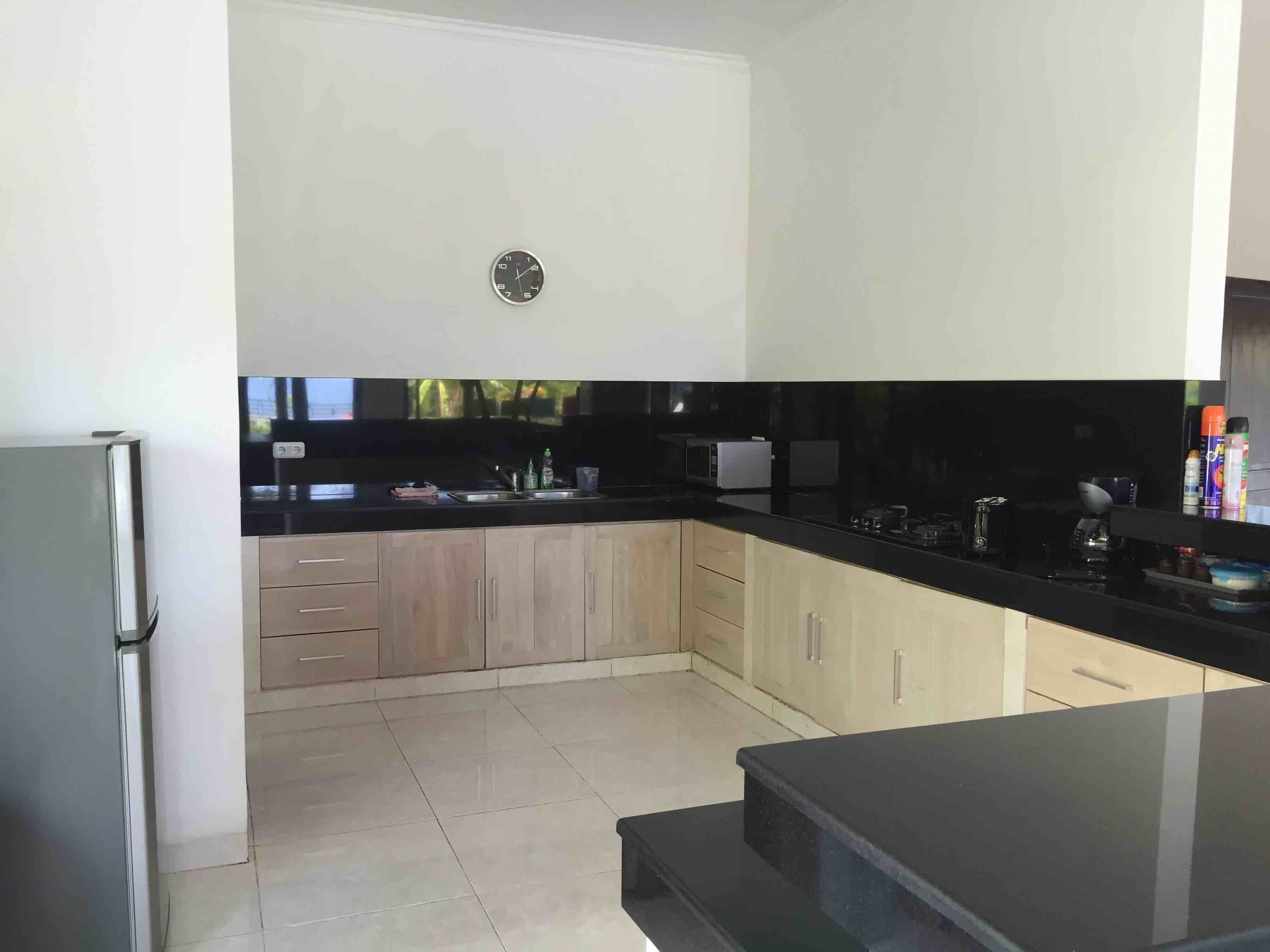Una cocina moderna con armarios de madera clara, encimera negra y electrodomésticos de acero inoxidable.