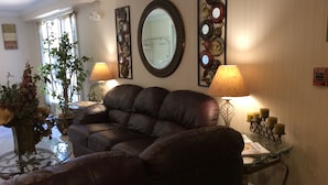 A living room with a leather sofa, two lamps, a mirror, and decorative wall art.