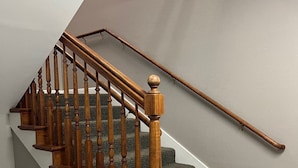 A wooden staircase with a handrail, carpeted steps, and a tiled floor.