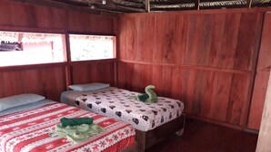 A room with two wooden beds, each with a patterned bedspread and pillows. - Alojamiento y tour en la Amazonia (Lago agrio)